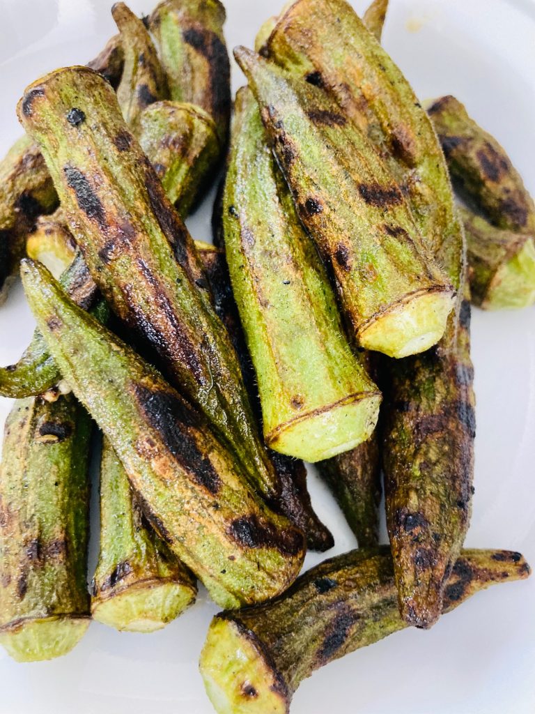 char-grilled okra piled on a white plate