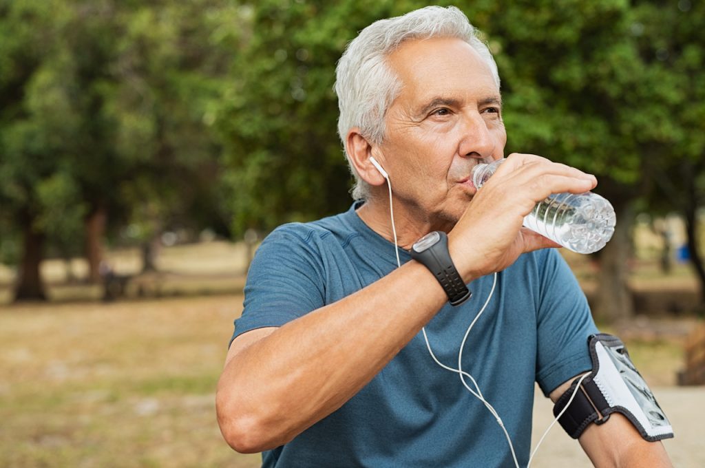 Active old man having a break during his jog routine outside.